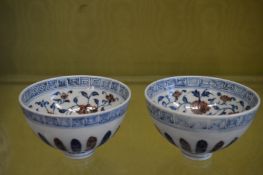 A pair of Chinese porcelain bowls decorated in iron red and blue with flowers.
