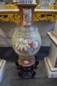 A very large Chinese famille verte baluster shaped vase on a wooden stand.