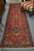 A Persian design runner, red ground with stylised decoration, 298cm x 92cm.