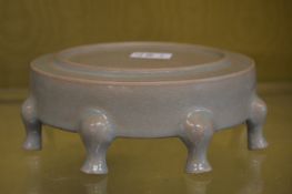 A Chinese celadon glazed circular stand with eight small curving feet.