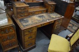 A Victorian walnut kneehole pedestal desk with upper section containing various drawers.
