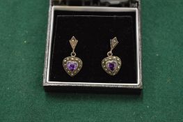 A pair of amethyst set heart shaped earrings.