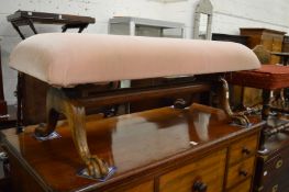 A long upholstered stool on cabriole legs with claw and ball feet.