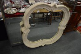 An unusual faux stone framed wall mirror of shaped outline.