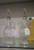 A pair of small cut glass decanters and stoppers with silver collars.