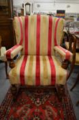 An oak framed open armchair upholstered with a striped material.