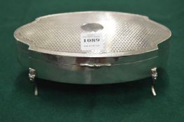 A engine turned decorated silver dressing table box with hinged cover on four scrolling feet.
