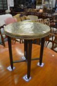An Eastern embossed brass table with folding base.