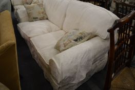 A large cream upholstered two seater settee.