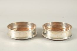 A PAIR OF SILVER CIRCULAR WINE COASTERS with wooden bases. 12cms diameter.