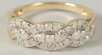 A 9CT YELLOW GOLD DIAMOND SET, INTERTWINING DRESS RING. Diamonds 0.25ct.