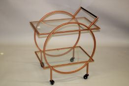 A TWO TIER METAL AND GLASS DRINKS TROLLEY on four wheels.