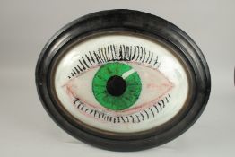 A REVERSE PAINTED GLASS OVAL EYE. 30cm high in a wooden frame.