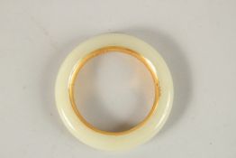 A CHINESE WHITE JADE AND GILT BANGLE. 8cms diameter.