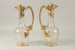 A GOOD PAIR OF ART DECO ENGRAVED GLASS AND GILT METAL CLARET JUGS, engraved with flowers. 31cms