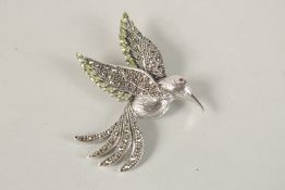 A SILVER PERIDOT HUMMING BIRD BROOCH.