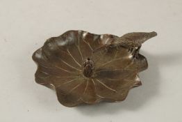 A BRONZE OKIMONO OF A BIRD ON A LILY PAD WITH LOTUS.
