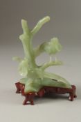 A CHINESE CARVED JADE GROUP ON HARDWOOD STAND, the group carved with pea hens on tree branches, jade