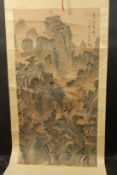 A CHINESE SCROLL PAINTING ON SILK, depicting a mountainous landscape with buildings, inscribed upper