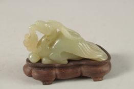 A CHINESE CARVED JADE FIGURE OF A MYTHICAL CREATURE on a wooden stand, jade 10cm long.