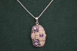 Decorative silver pendant and chain set with purple stones in a flower head design.