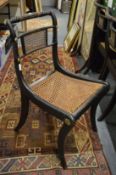 A set of three Regency ebonised and cane seated dining chairs.