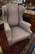 A wing armchair on carved claw and ball feet.