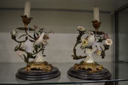 An unusual pair of Continental ormolu and porcelain candelabra of naturalistic form depicting