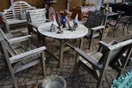 A wooden circular patio table with four matching armchairs.