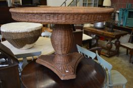 A large wicker circular pedestal table.
