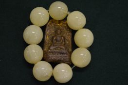 A bead bracelet and a carved stone Buddha.