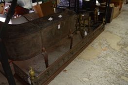 A pierced steel fender, an unusual fender on curving legs, pair of fire dogs and brass candelabra.