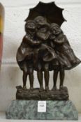 An amusing cast bronze group of three girls sheltering under an umbrella mounted on a marble base.