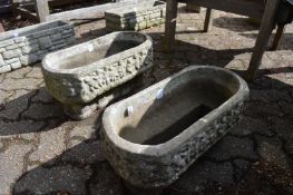 A pair of reconstituted stone trough shaped planters.