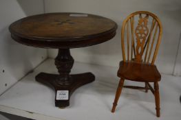 A miniature walnut circular tilt-top dining table together with a miniature wheel back chair.