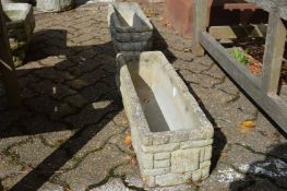 A pair of reconstituted stone trough shaped planters.