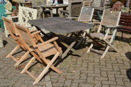 A hardwood garden table with folding base together with a set of four folding armchairs.