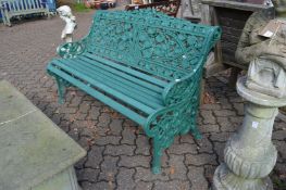 A green painted cast metal garden bench in the Victorian style.