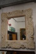 A wall mirror with decorative carved wood frame.
