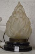 A table lamp with flaming torch glass shade.