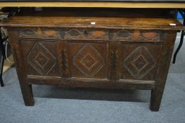 An 18th century oak coffer with carved triple panelled front, traces of painted decoration.