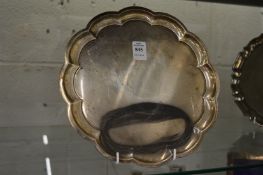 A silver waiter with scroll border on three curving feet, 20oz.