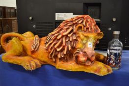 A large fibre glass model of a sleeping lion together with a limited edition Absolut vodka bottle.