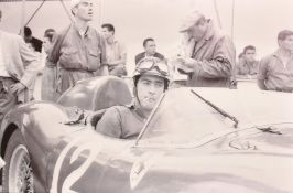 A printed image of Luigi Musso seated in a Formula 1 Ferrari in a pit lane, 38