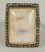 A LARGE SILVER AND SILVER GILT DRESS RING set with a large rectangular moonstone surrounded by