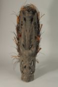 A SEPIK CARVED WOOD FIGURE, a man holding a headdress with animal mask. 60cms high.
