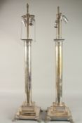 A GOOD PAIR OF SILVER PLATE COLUMN LAMPS on square stepped bases with claw feet.