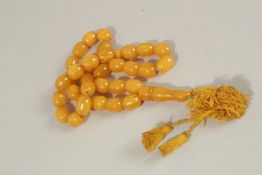 A STRING OF THIRTY-THREE AMBER BEADS. Weight 102gms.