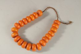 A SET OF LARGE AMBER TYPE BEADS.