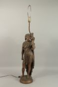 A SPELTER MODEL OF AN ARAB MAN holding a vessel, on a circular base, as a lamp. 70cms high.